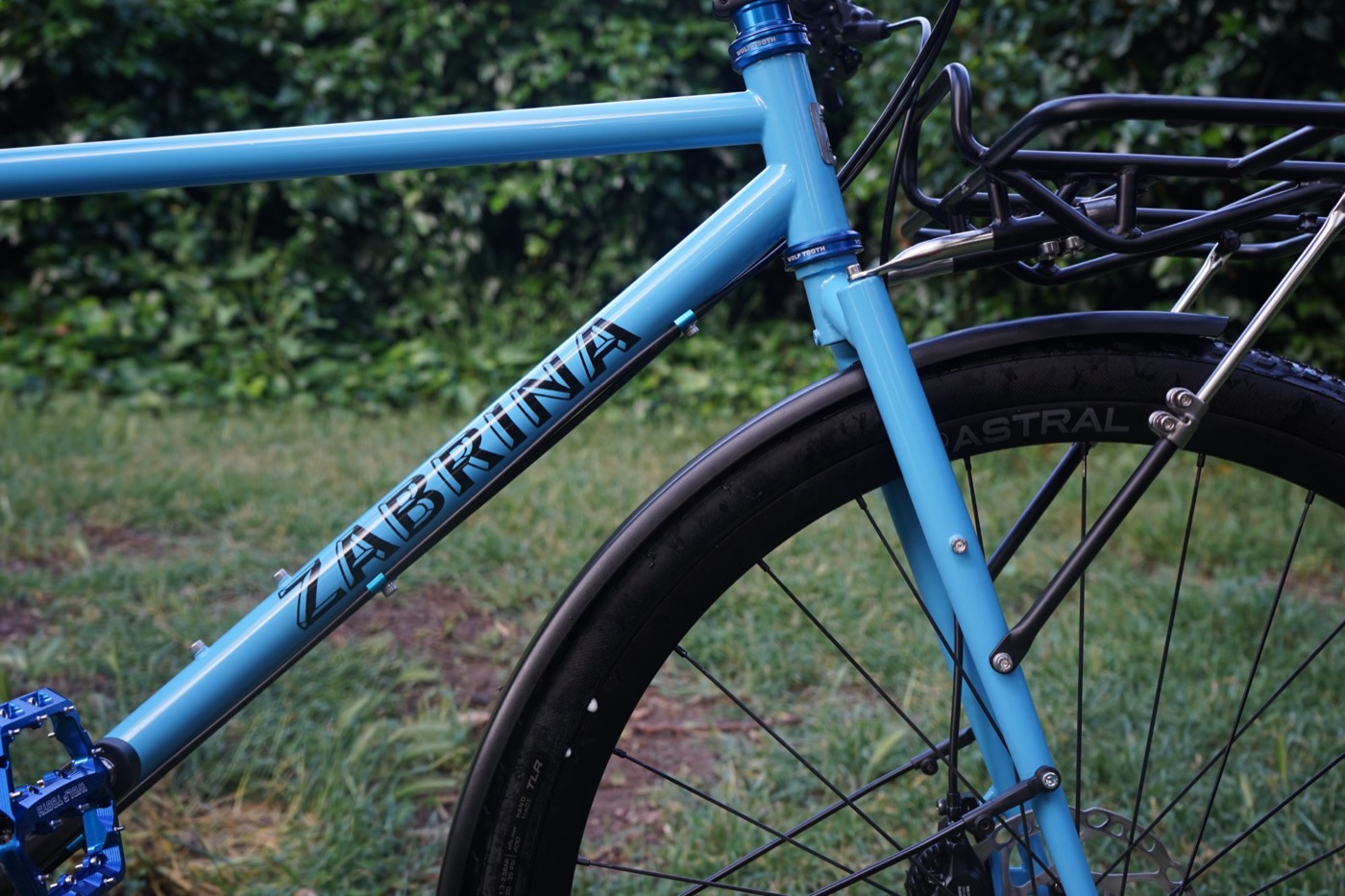 Black Zabrina lettering on a sky blue down tube beside a fender and front rack