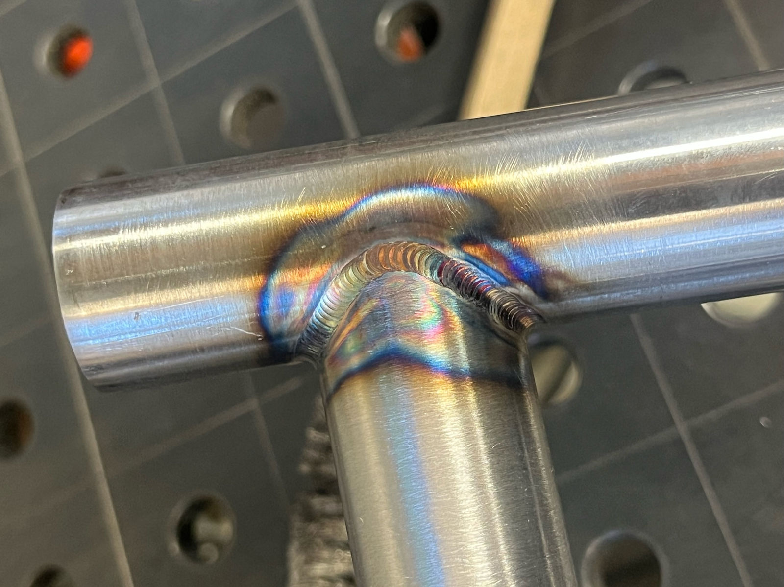 Fresh weld bead on a steel tube junction over the fixture table