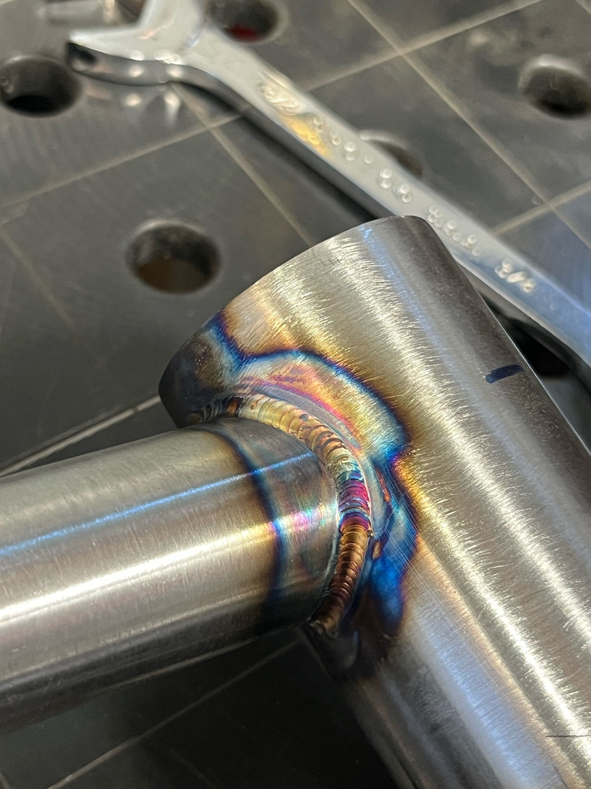 Weld wrapping a mitered tube on the welding table, wrench nearby