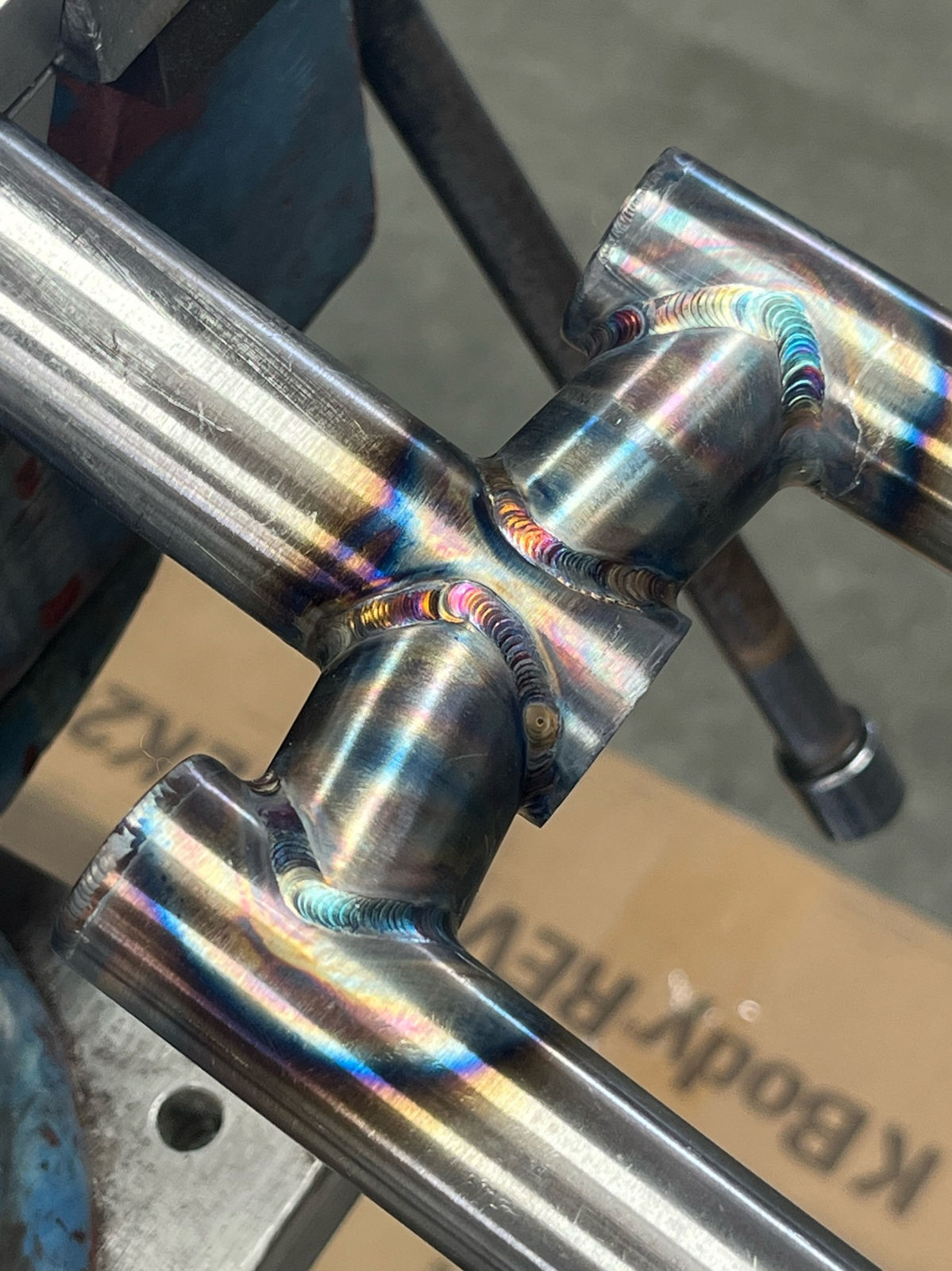 Seat cluster welds on a raw steel frame held in a vise