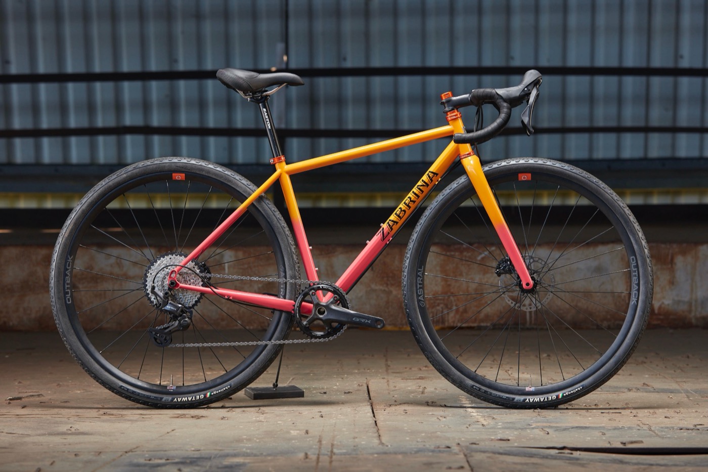 Orange-to-pink fade Zabrina road bike in a warehouse