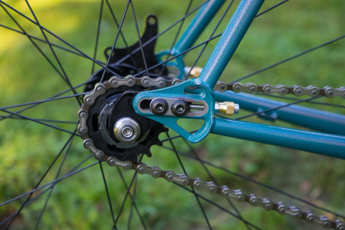 Sliding dropout with brass chain tensioner on the teal single speed