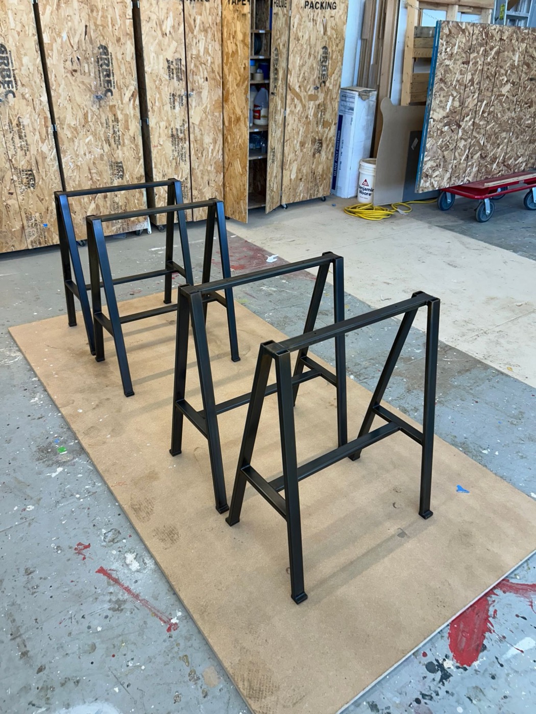 Four dark steel A-frame trestle table legs on the shop floor